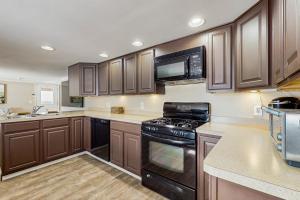 a kitchen with wooden cabinets and black appliances at 12 Mi to Lake George! Quiet Adirondack Escape in Fort Ann +16 photos