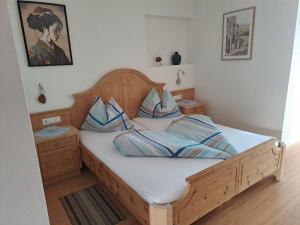 a bedroom with a wooden bed with blue pillows at B&B Gasthaus Lieg in Castelrotto +31 photos