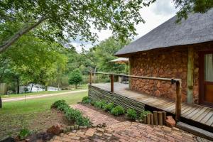 a stone house with a wooden porch on the side of it at Mologa River Lodge in Rust de Winter