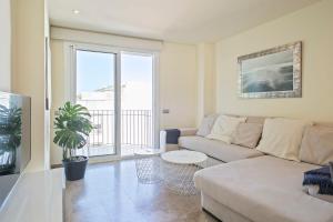 a living room with a couch and a large window at Beach Penthouse Sitges in Sitges