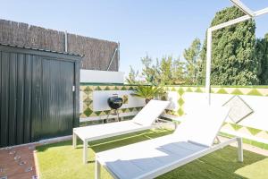 a patio with two white chairs and a fence at Beach Penthouse Sitges in Sitges
