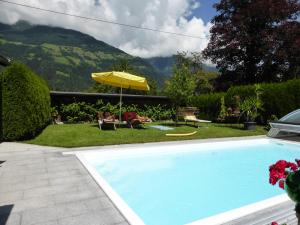 uma piscina com um guarda-sol e vista para uma montanha em Ferienwohnungen Kolbitsch em Greifenburg