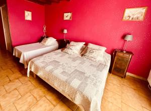 a bedroom with two beds and a red wall at Gîte LES GOUTTES 2 chambres 2 SDB in Courzieu