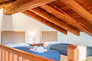 two beds in a room with wooden ceilings at La Meridiana in Carrù