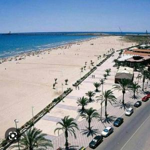 a beach with palm trees and cars parked on it at Duplex Ático con terraza y BBQ in Puerto de Sagunto