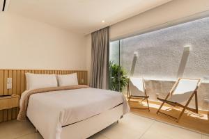 a bedroom with a bed and a balcony with chairs at Onda Lofts in Búzios