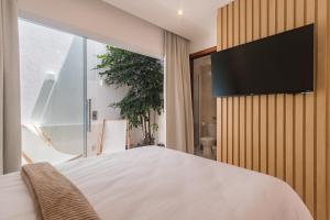 a bedroom with a bed and a flat screen tv on a wall at Onda Lofts in Búzios