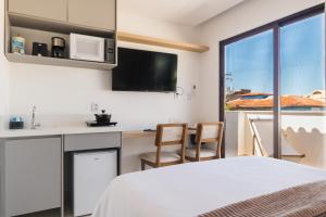 a bedroom with a bed and a kitchen with a window at Onda Lofts in Búzios