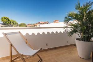 a white chair sitting on a balcony with a plant at Onda Lofts in Búzios