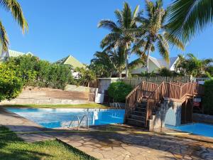 a resort pool with stairs and palm trees at La splendide Coralline in La Saline Les hauts 