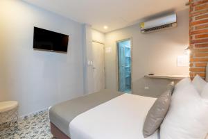 a bedroom with a white bed and a television at Hotel Boutique ADAZ in Santa Marta
