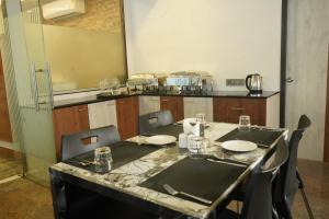 a dining room with a table and chairs and a kitchen at Sesha Residency in Chennai