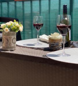 two glasses of wine sitting on a table with flowers at Local-Lux Premium Apartment- 2 Bedrooms Balcony -2 Private Parking in Kecskemét