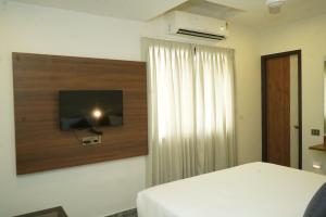 a bedroom with a bed and a television on a wall at Sesha Residency in Chennai