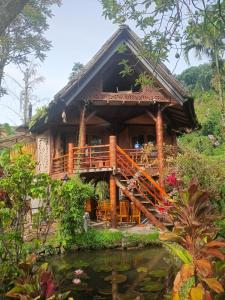 a house with a pond in front of it at SUMATRA ECORESORT in Bukittinggi