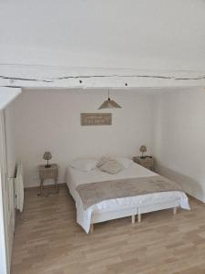 a white bedroom with a bed and two tables at Chez collette in Chablis