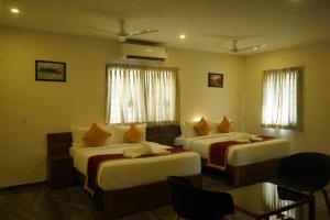 a hotel room with two beds and a table at Sesha Residency in Chennai