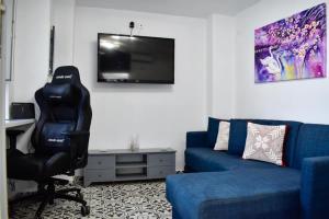 a living room with a blue couch and a tv at Stella's House in Skopelos Town