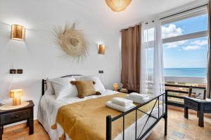 a bedroom with a bed with a view of the ocean at Adrar Lodge - Boutique Guesthouse with Sea View in Tamraght Ouzdar
