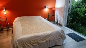 a bedroom with a bed with an orange wall at La Kaz Zarlor in Saint-Paul