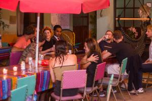 a group of people sitting around a table with an umbrella at Hierba De Conejo Hostel in Oaxaca City