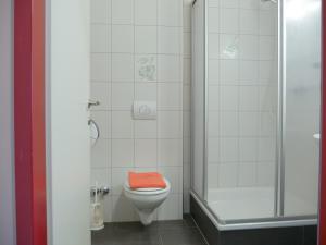 a bathroom with a toilet with an orange seat at Hotel Linde-Sinohaus in Lustenau +22 photos