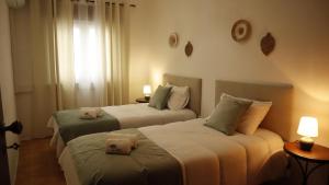 two beds in a hotel room with two lamps at Refúgio da Azinheira in Torrão