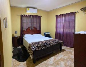 a bedroom with a large bed with purple curtains at Royal Properties Link in Crooked Tree