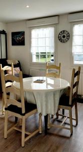 a dining room table with chairs and a clock on the wall at Ti Ar Skol, chambre d'hôtes in Huelgoat