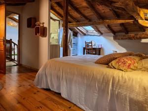 a bedroom with a white bed in a room with wooden floors at 3 chambres d'hôtes de charme avec jacuzzi & sauna au Clos de la Lèze in Lézat-sur-Lèze