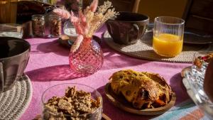 a table with a pink table cloth with food and orange juice at 3 chambres d'hôtes de charme avec jacuzzi & sauna au Clos de la Lèze in Lézat-sur-Lèze
