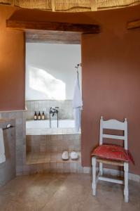 a bathroom with a tub with a chair and a shower at Awasi Atacama in San Pedro de Atacama