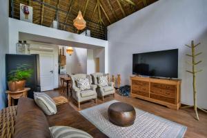 a living room with a couch and a flat screen tv at Mologa River Lodge in Rust de Winter
