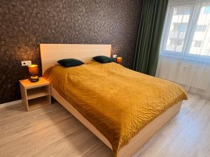 a bedroom with a large bed with a yellow blanket at home&stay - free parking in Trenčín