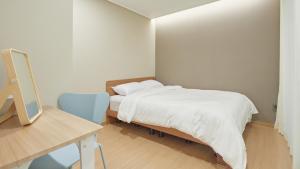 a bedroom with a bed and a desk with a mirror at Haeundae Elbonz in Busan