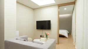 a living room with a couch and a tv on a wall at Haeundae Elbonz in Busan