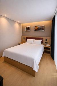 a bedroom with a large bed with white sheets at Haeundae Elbonz in Busan