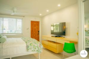 a white bedroom with a bed and a television at Gulfside Resort. Unit 10 in St. Pete Beach