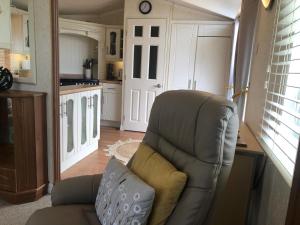 a living room with a chair and a kitchen at 29 The Beeches in Gilcrux