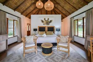 a bedroom with a bed and two chairs at Mologa River Lodge in Rust de Winter