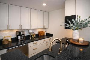 a kitchen with white cabinets and a black counter top at Luxury Rooftop Pool & Dock Steps to Downtown in Annapolis