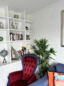 a living room with a red chair and a book shelf at Lakefront Lodge w SUP & Fishing Access Cotswolds in Gloucestershire