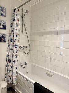 a bathroom with a bath tub and a shower curtain with a boat at Lakefront Lodge w SUP & Fishing Access Cotswolds in Gloucestershire +24 photos
