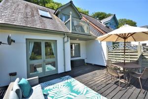 a wooden deck with a table and an umbrella at 2 Bed in Little Petherick oc-p00635 in Little Petherick