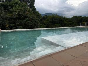 a swimming pool with clear blue water and trees at Apartamento duplex villa 19 de lujo in Armenia