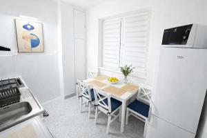 a white kitchen with a table and a refrigerator at Apartman Cañas Modrá Víla in Rimavská Sobota