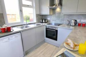 a kitchen with white appliances and a plate of food on the counter at Forest Edge 4 Bedroom Select Lodge in Saint Leonards