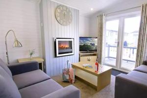 a living room with a couch and a clock on the wall at Forest Edge 4 Bedroom Select Lodge in Saint Leonards
