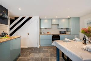 a kitchen with blue cabinets and a table with wine glasses at 3 Bed in St. Ives oc-marhou in St Ives