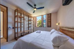 a bedroom with a white bed with a ceiling fan at Condominios Punta Morelos in Brisas de Zicatela